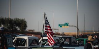 A Shot of the American Flag on Top of a Chevy Pickup Truck with Rows of Trucks Next to It