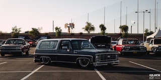 Three Quarters View of a Chevy Vehicle at a Parking Lot with a Row of Pickup Trucks behind It