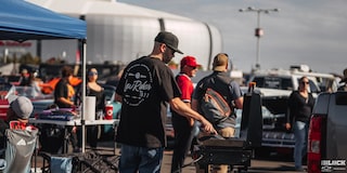 A Man Is Doing Barbeque at Dino’s Git Down Event with Cars and People Seen at the Area