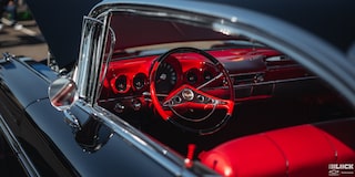 A Black Chevrolet Vehicle Steering Wheel and Red Interior Seen through the Window