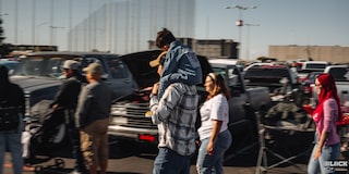 A Man Carrying His Son on His Shoulders with a Woman Next to Him Walking at Dino’s Git Down Event