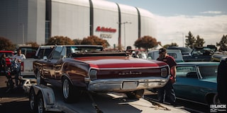 Rear View of a Red Pontiac Vehicle on Top of a Trailer at a Parking Lot