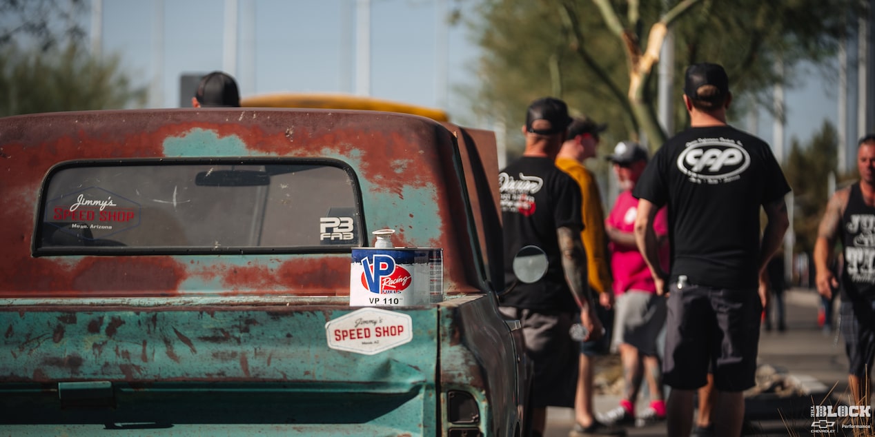 Three Quarters Rear View of a Rusty Pickup Truck with a Couple of Men Standing in Front