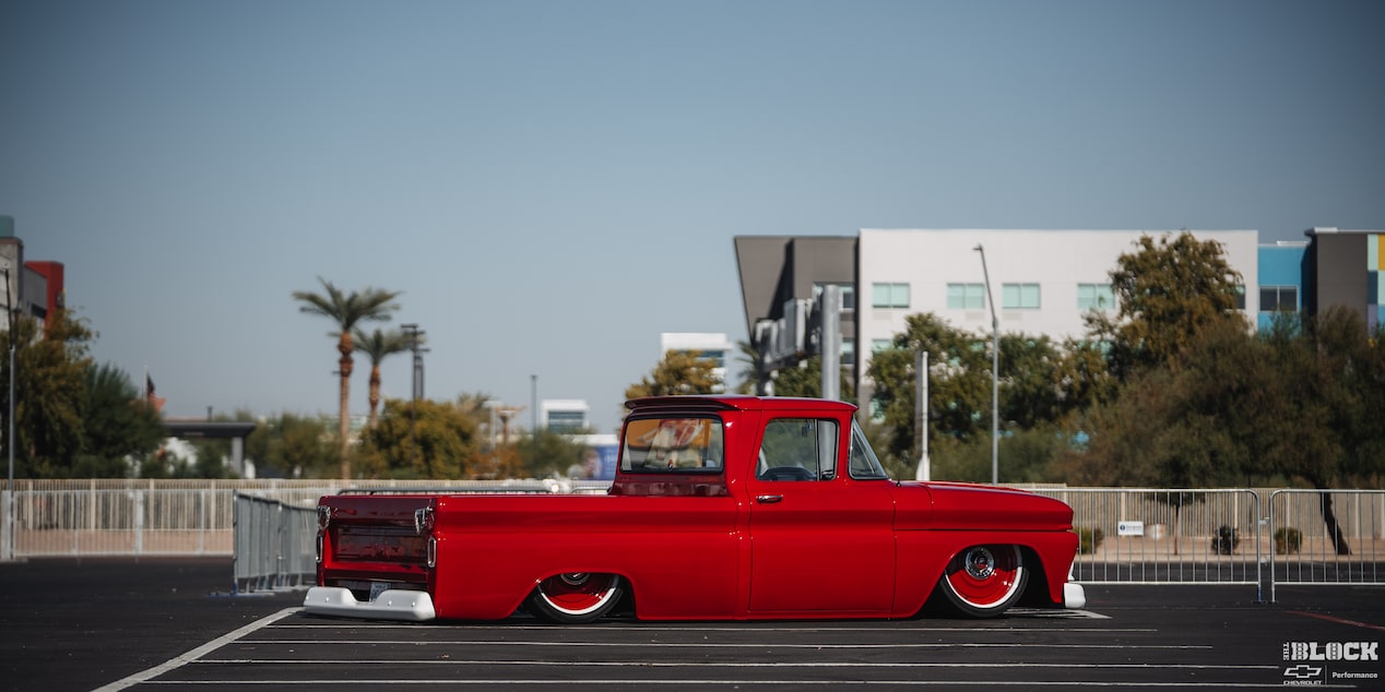 Side View of a Shiny Red Pickup Truck on the Road under a Clear Blue Sky