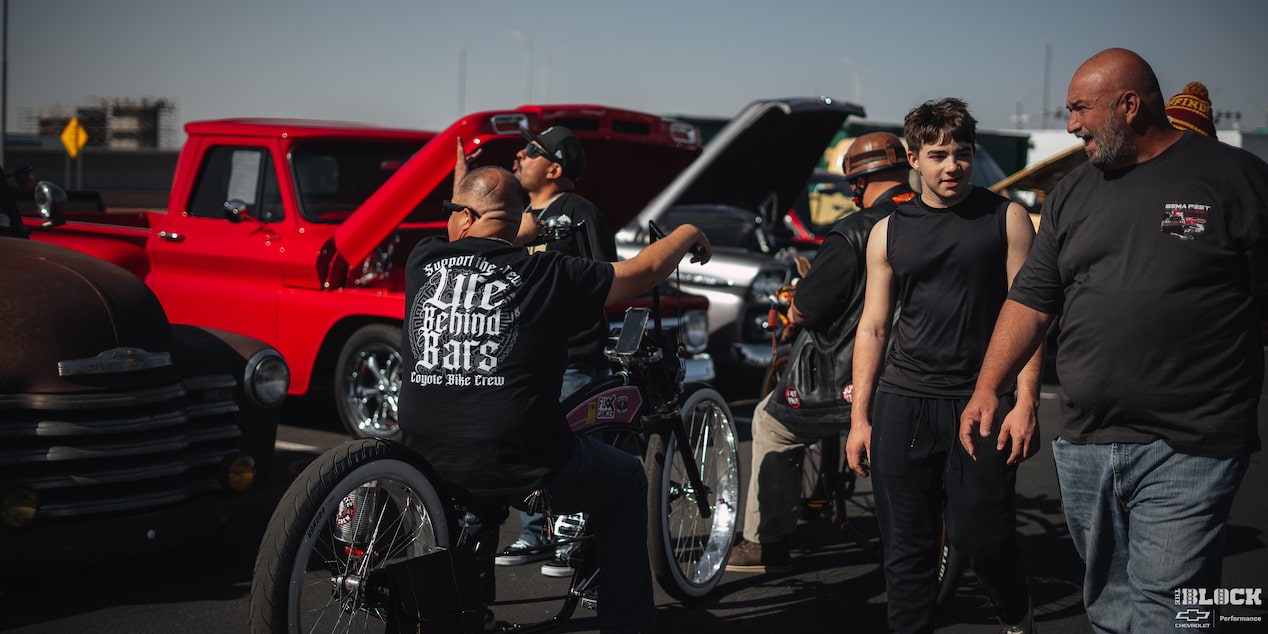 A Couple of Men Walking around and Talking with a Line of Cars with Their Hood Open Seen in the Distance