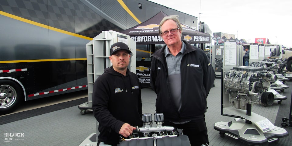 Two Chevrolet Performance Representatives Standing with a 525 RLB Chevrolet Performance Engine