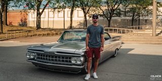 A Man Wearing a Hat and Sunglasses Standing Next to a Silver Chevy Impala