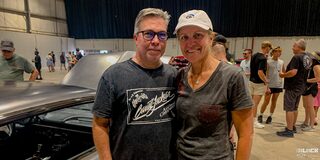 A Man with Glasses and a Woman with a White Cap Taking a Picture at an Event