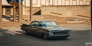 Three Quarters View of a 1959 Grey Chevy Impala in Front of a Building during Sunset