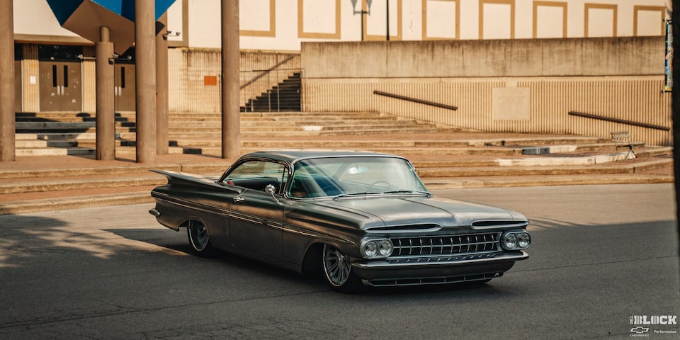 Three Quarters View of a 1959 Grey Chevy Impala in Front of a Building during Sunset
