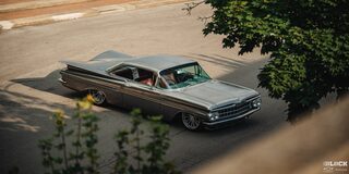 Three Quarters View of a 1959 Grey Chevy Impala under the Shade Seen from Far Away