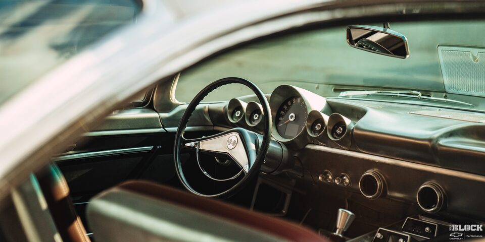 A View of the Front Steering Wheel and Control Board of a 1959 Chevy Impala Seen from outside the Window