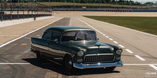 Front Three Quarters View of a Dark Green 1955 Chevrolet on a Racetrack