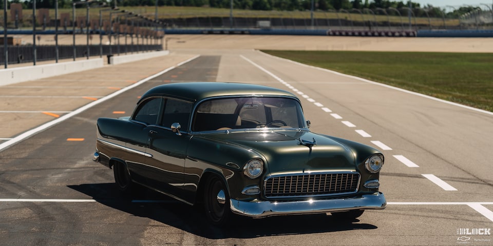Front Three Quarters View of a Dark Green 1955 Chevrolet on a Racetrack