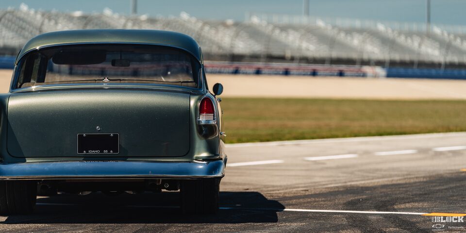 The Rear View of a 1955 Chevrolet on a Racing Track at the Left Edge of the Frame