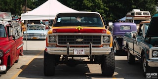 Vista delantera de una gran camioneta Chevy clásico con enormes neumáticos y "Farm Use" (uso agrícola) escrito en Rojo en la placa delantera en los Summit Racing Nationals