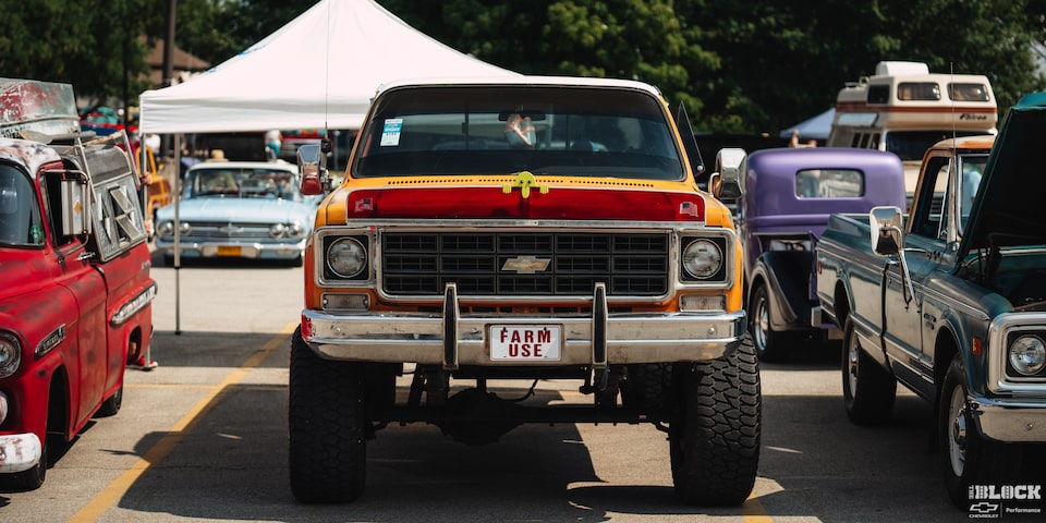 Vista delantera de una gran camioneta Chevy clásico con enormes neumáticos y "Farm Use" (uso agrícola) escrito en Rojo en la placa delantera en los Summit Racing Nationals