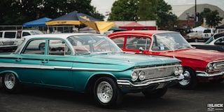 Un par de autos Chevy clásicos, uno Azul y otro Rojo, estacionados en los Summit Racing Nationals