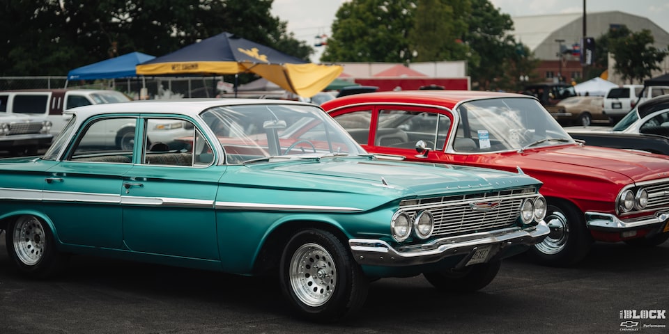 Un par de autos Chevy clásicos, uno Azul y otro Rojo, estacionados en los Summit Racing Nationals