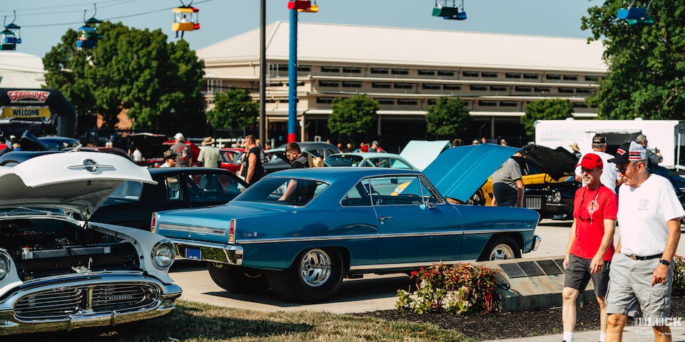 Una gama de autos Chevy con el cofre abierto con un auto Chevy Azul clásico en el centro del cuadro en los Summit Racing Nationals