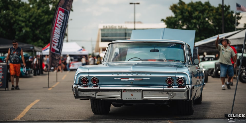 Vista trasera de un clásico Chevy Azul estacionado con el cofre abierto en exhibición en los Summit Racing Nationals.