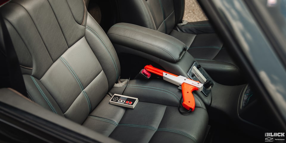 Vista del interior de un Chevy clásico con una consola de juegos Nintendo Entertainment System integrada en la consola central con un Zapper NES conectado a ella.