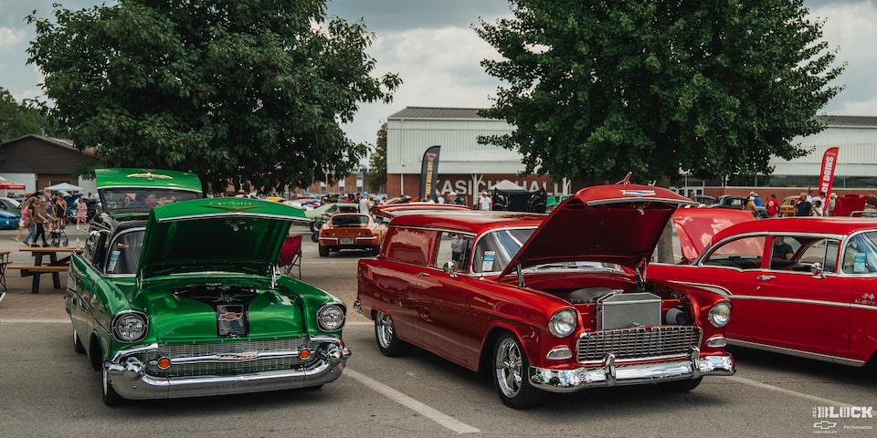 Una gama de autos Chevy clásicos estacionados con los cofres abiertos en los Goodguys Summit Racing Nationals