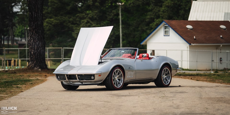 Front View of a 1969 Silver Chevy Corvette with the Engine Hood Open with a House in the Background