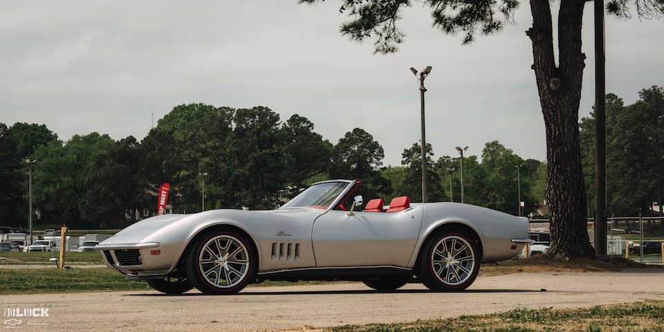 Side View of a 1969 Silver Chevy Corvette Parked with Trees in the Background