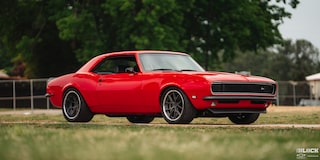 Three Quarters View of a 1968 Orange Chevy Camaro on a Grassy Plain