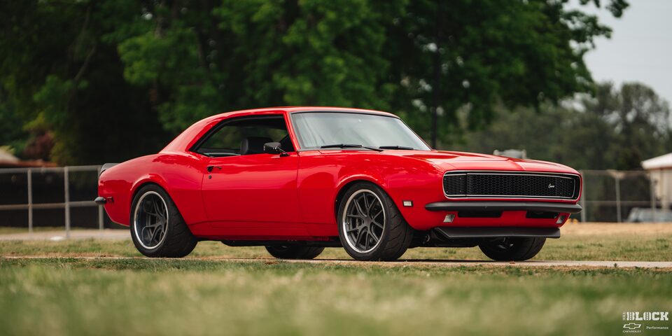 Three Quarters View of a 1968 Orange Chevy Camaro on a Grassy Plain