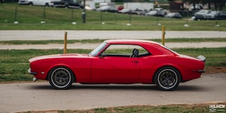 Left Side View an Orange 1968 Chevy Camaro Next to Grasses
