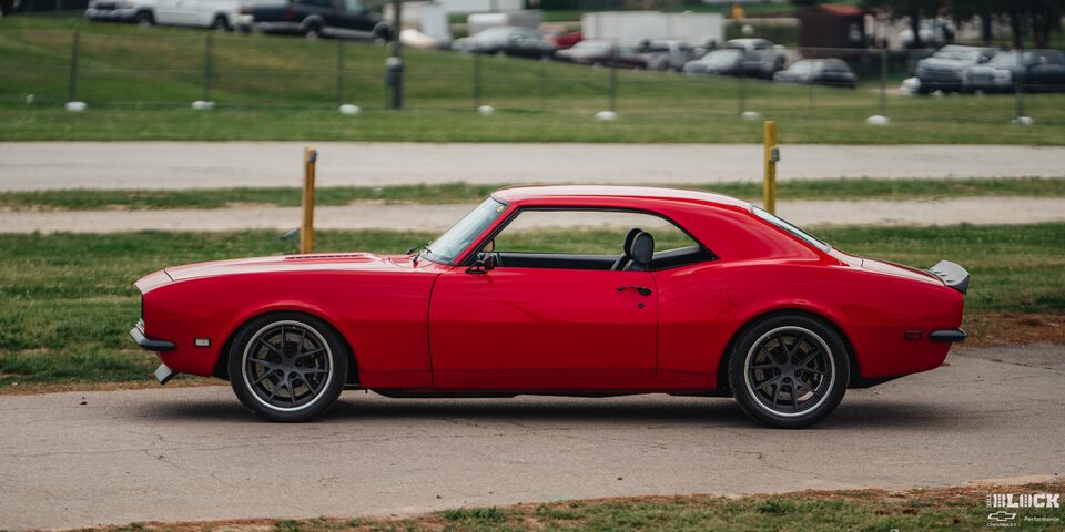 Left Side View an Orange 1968 Chevy Camaro Next to Grasses