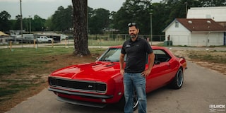 A Man Wearing a Black T-Shirt Standing in Front of an Orange Chevy Camaro