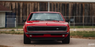 Front Eye Level View of a 1968 Orange Chevy Camaro in Front of a Fence