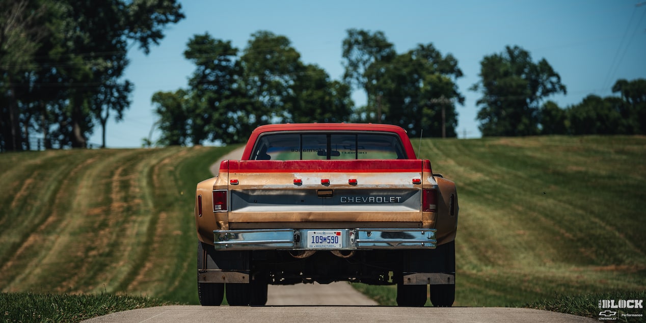 Eye-Level Rear View of a Red Chevy Performance Silverado Surrounded by Grassy Plain