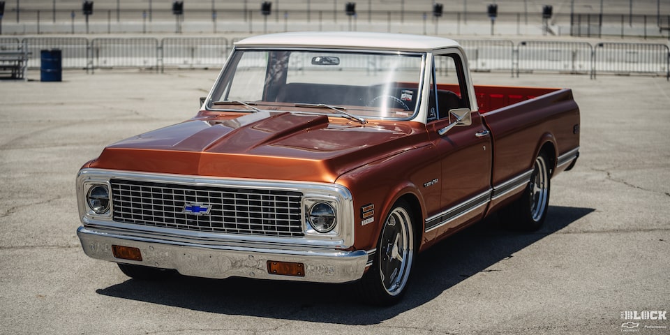 Vista de tres cuartos de una pickup Chevy C10 Naranja en un terreno vacío