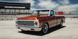 Vista detallada de tres cuartos de una pickup Chevy C10 Naranja bajo un sol radiante