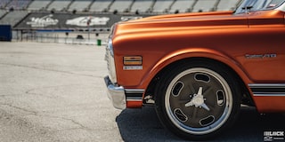 Vista frontal izquierda de una pickup Chevy C10 Naranja con un estadio en la distancia