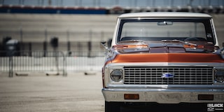 Vista frontal a la altura de los ojos de una pickup Chevy C10 Naranja a un lado del cuadro
