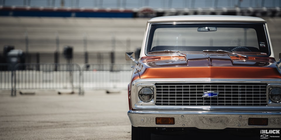 Vista frontal a la altura de los ojos de una pickup Chevy C10 Naranja a un lado del cuadro