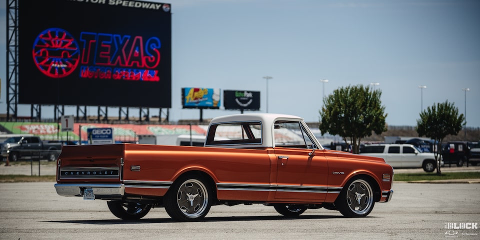 Vista trasera de tres cuartos de una pickup Chevy C10 Naranja en un estacionamiento