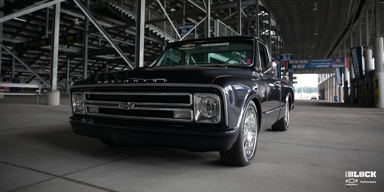 Vista en primer plano de una Chevrolet C10 1967 en Negro con un motor armado L8P, estacionada debajo de las gradas en una pista de carreras