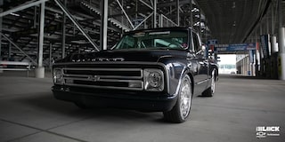Vista en primer plano de una Chevrolet C10 1967 en Negro con un motor armado L8P, estacionada debajo de las gradas en una pista de carreras