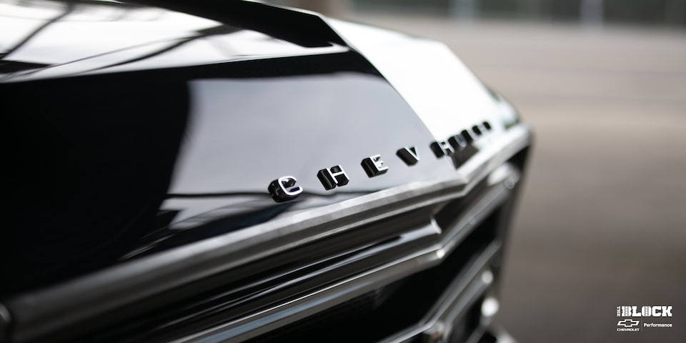 Vista en primer plano del cofre de una Chevrolet C10 1967 en Negro, con el adorno del cofre que dice "Chevrolet"