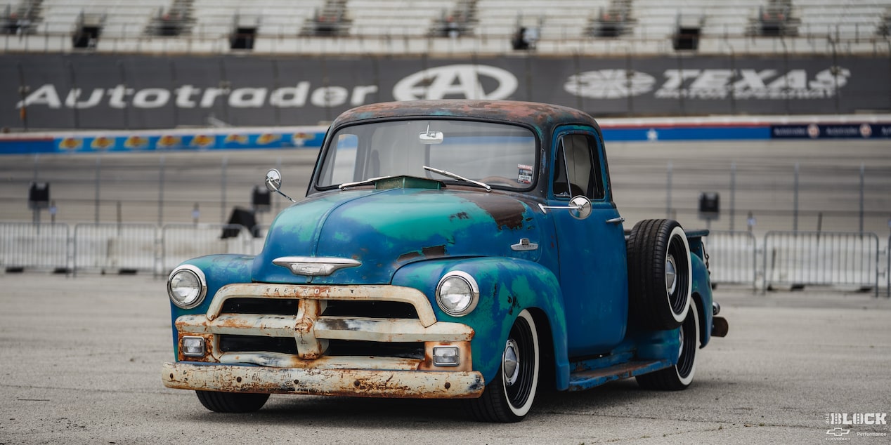 Three Quarters View of a Rusty 1955 Chevy Pickup Truck on the Side of a Racetrack