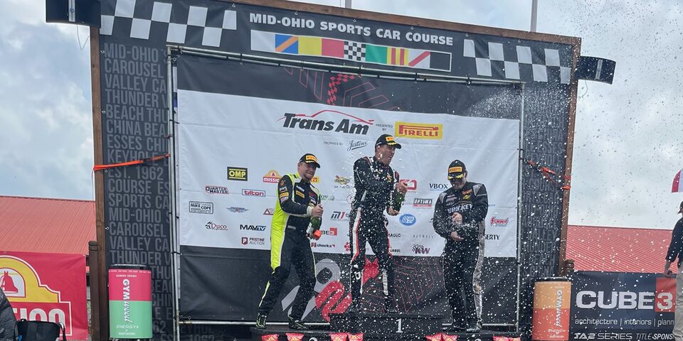 Rinke (right) celebrates on the podium at Mid-Ohio Sports Car Course after navigating around the 13-turn, 2.258-mile circuit in treacherous conditions.