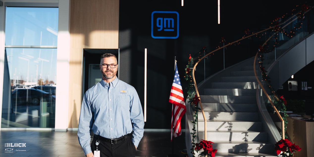 A GM Employee Poses in Front of a Holiday Display and American Flag in the Lobby of the GM Charlotte Technical Center.