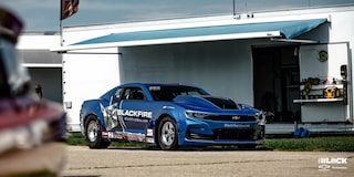 Wide Front Three-Quarters View of a Chevrolet Copo Camaro Parked Next to a Trailer Under an Awning