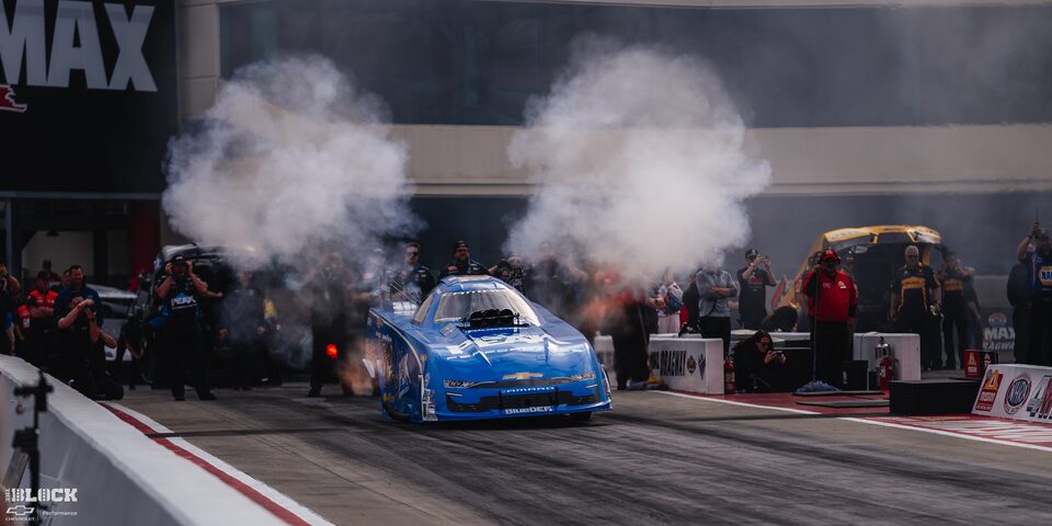 Front View of John Force's Chevrolet Funny Car Accelerating on the Track at Charlotte Motor Speedway
